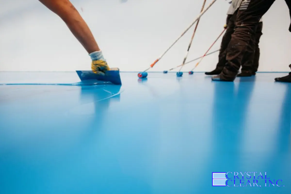 an image of a bright light blue epoxy being troweled over a garage floor, it'd very clean and colorful