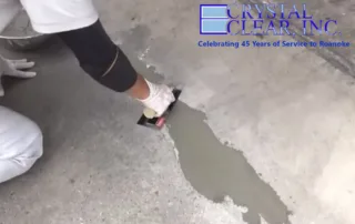 Image of a woman of color using a trowel to repair a concrete floor