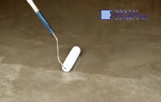 an image of a woman applying a ultra clear epoxy concrete basement floor coating in Roanoke VA