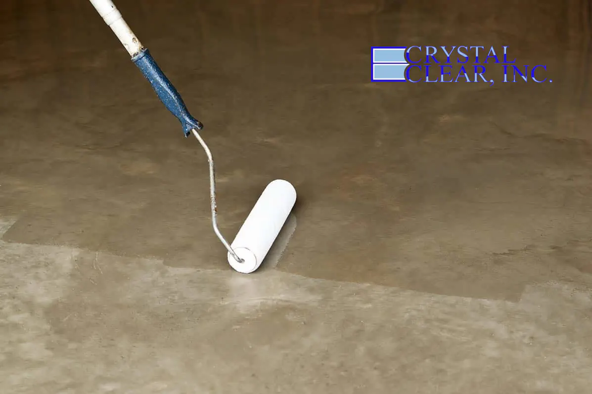 an image of a woman applying a ultra clear epoxy concrete basement floor coating in Roanoke VA