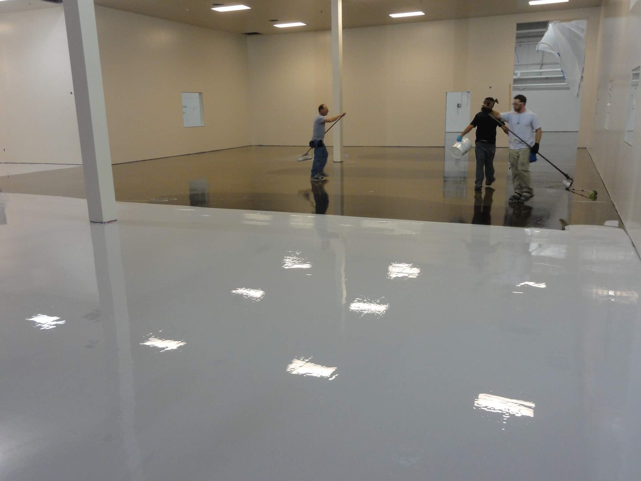 an image of a black woman and a Latino man performing Commercial Floor Services in a warehouse, they are looking at the camera and smiling widely